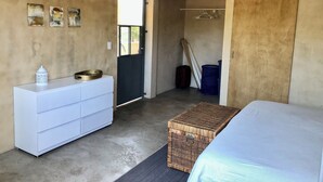 A bedroom with a bed, a dresser, a basket, a wardrobe, and a door leading to another room. -  Surrounded by beautiful views + 7 min. walk to the beach (Lo de Marcos)