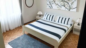 A neatly arranged bedroom with a bed, bedside tables, a mirror, and a wall-mounted artwork. - Holiday apartment Flat with pool (Pješćana Uvala)