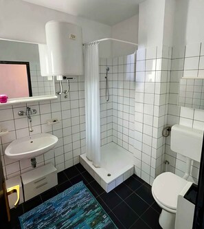 Une salle de bain moderne équipée d’un lavabo, de toilettes, d’une douche et d’un miroir.