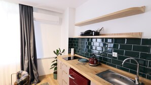 A modern kitchen with a wooden countertop, a red dishwasher, a black tiled backsplash, and a stainless steel sink. - Evra Suites (İstanbul)