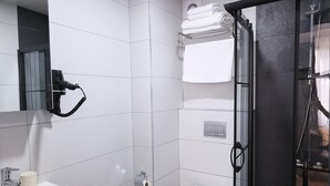 A modern bathroom with a white sink, toilet, and glass shower enclosure. - Evra Suites (İstanbul)