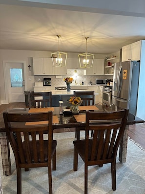 A modern kitchen with a central island, wooden chairs, and pendant lighting. - Historic Mattsville in Carmel (Carmel)