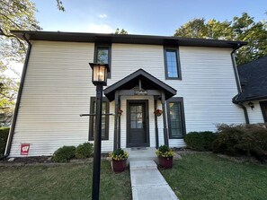 A two-story house with a front porch, a mailbox, and a street sign.