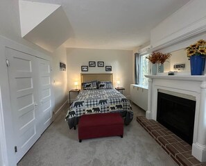 Een slaapkamer met een bed, een open haard, een rode bank en ingelijste foto's aan de muur.