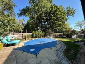 A backyard with a circular pool, a wooden deck, and a fenced area.
