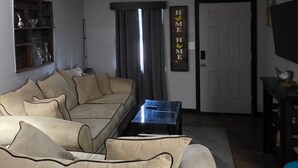 A living room with a beige sofa, a coffee table, and a TV on a stand.