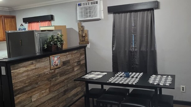 A modern kitchen with a wooden island, a dining table with chairs, and a built-in air conditioning unit.
