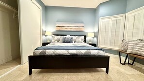 A bedroom with a bed, two bedside lamps, a nightstand, a window with blinds, and a view of the outside. - Modern Luxe King Suite in Heart of San Jose (San Jose)