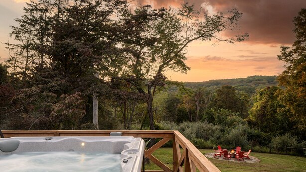 Ein Whirlpool auf einer Holzterrasse mit Blick auf eine bewaldete Landschaft.