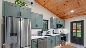 A modern kitchen with stainless steel appliances, green cabinets, and a wooden ceiling. - Finger Lakes Luxury Couples Retreat with Sauna, Hot tub and Cold Plunge (Alpine)
