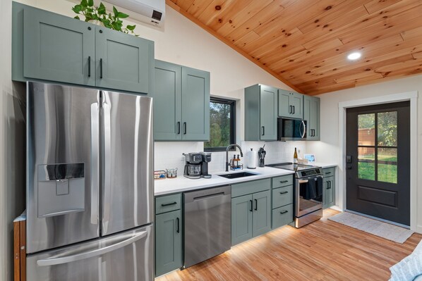 A modern kitchen with stainless steel appliances, green cabinets, and a wooden ceiling. - Finger Lakes Luxury Couples Retreat with Sauna, Hot tub and Cold Plunge (Alpine)