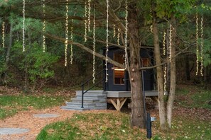 A treehouse with a staircase leading up to it, surrounded by trees and a forested area. - Finger Lakes Luxury Couples Retreat with Sauna, Hot tub and Cold Plunge (Alpine)