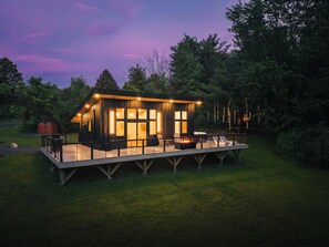 A modern cabin with a deck, large windows, and outdoor seating.