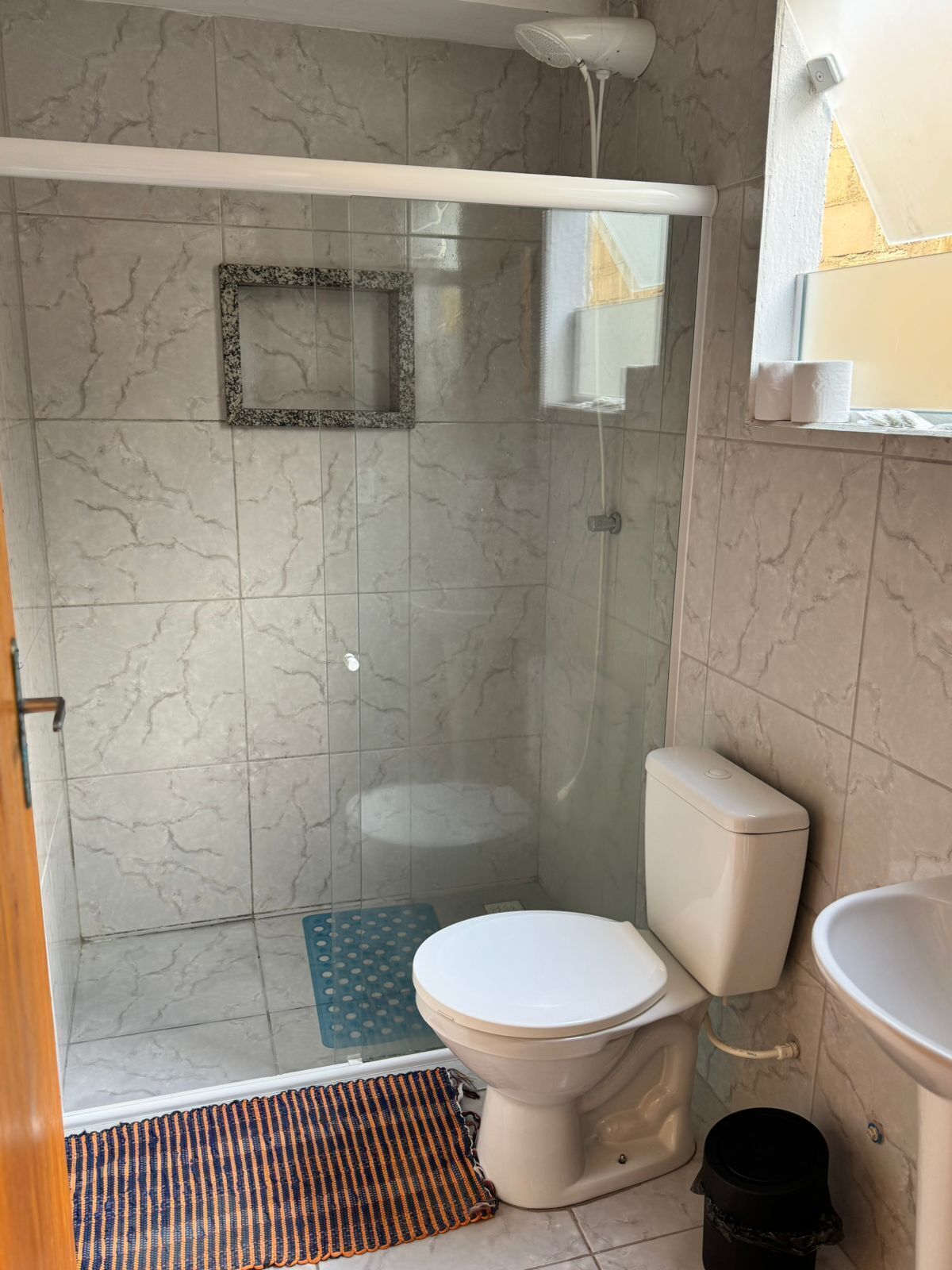 A bathroom with a glass-enclosed shower, a toilet, and a sink.