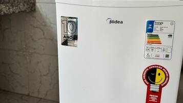 A white refrigerator with a 10-year warranty sticker, a sticker indicating it's energy efficient, and a red sticker with a light bulb and the text 'PROCEL'.