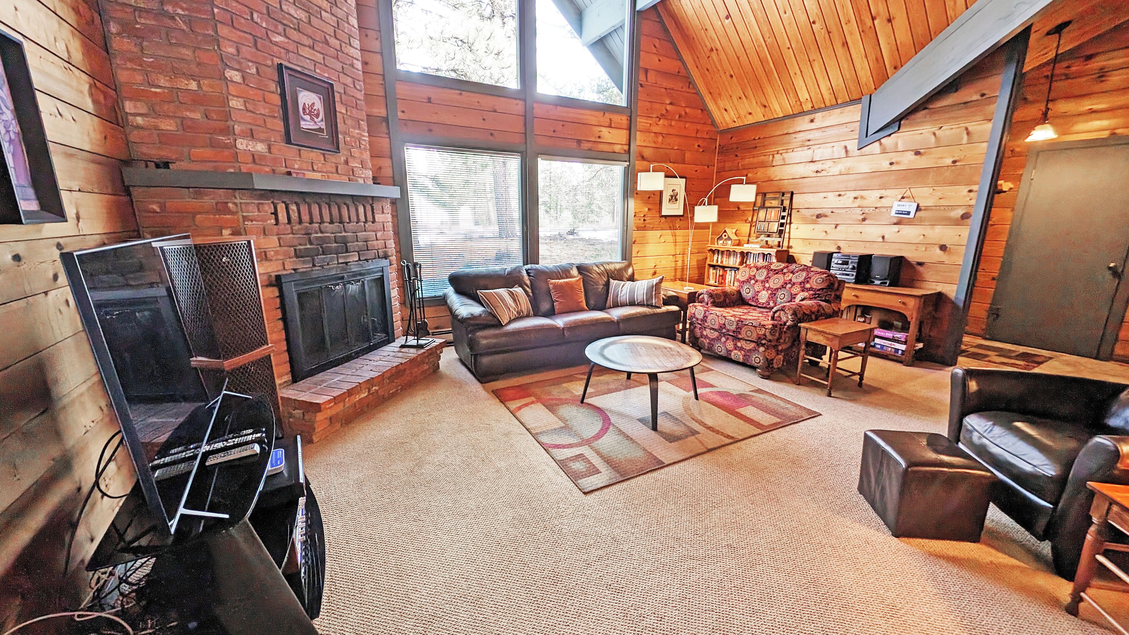 A cozy living room with a fireplace, leather sofas, a coffee table, and a television.