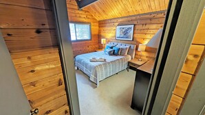 A wooden cabin bedroom with a bed, bedside lamps, and a framed picture on the wall. - Lava Top 1 - Updated Cabin, SHARC, Pet Friendly, Walk to SHARC (Sunriver)