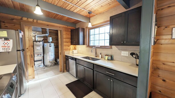 A modern kitchen with wooden cabinets, stainless steel appliances, and a large window providing natural light. - Lava Top 1 - Updated Cabin, SHARC, Pet Friendly, Walk to SHARC (Sunriver)