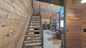 A wooden staircase leading to a living area with a fireplace, sofa, and television. - Lava Top 1 - Updated Cabin, SHARC, Pet Friendly, Walk to SHARC (Sunriver)