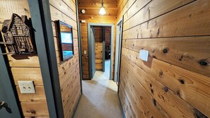 A narrow hallway with wooden walls, a ceiling light, and a door leading to another room. - Lave Top 1 - Updated Cabin, SHARC, Pet Friendly, Walk to SHARC (Sunriver)