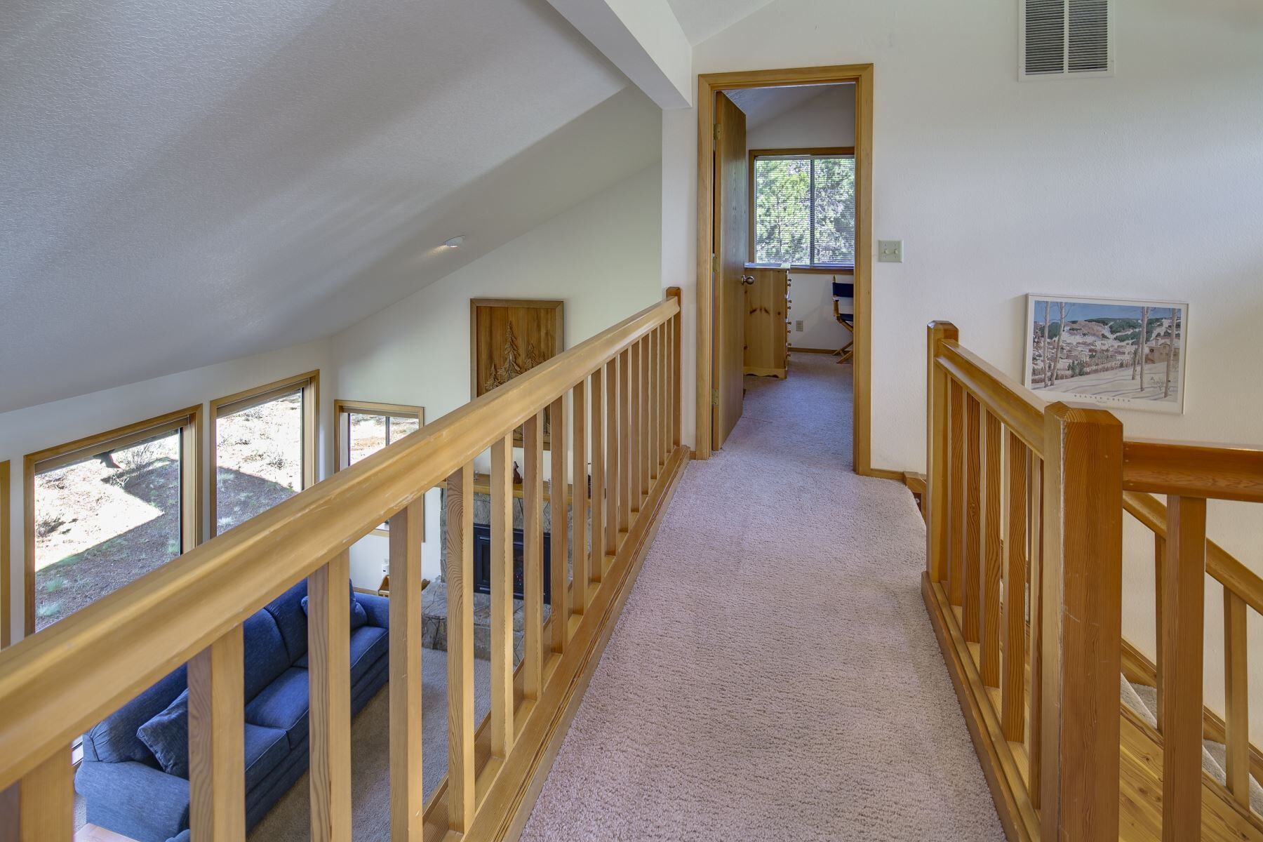 Una escalera con barandillas de madera que lleva a un dormitorio con ventana y puerta.