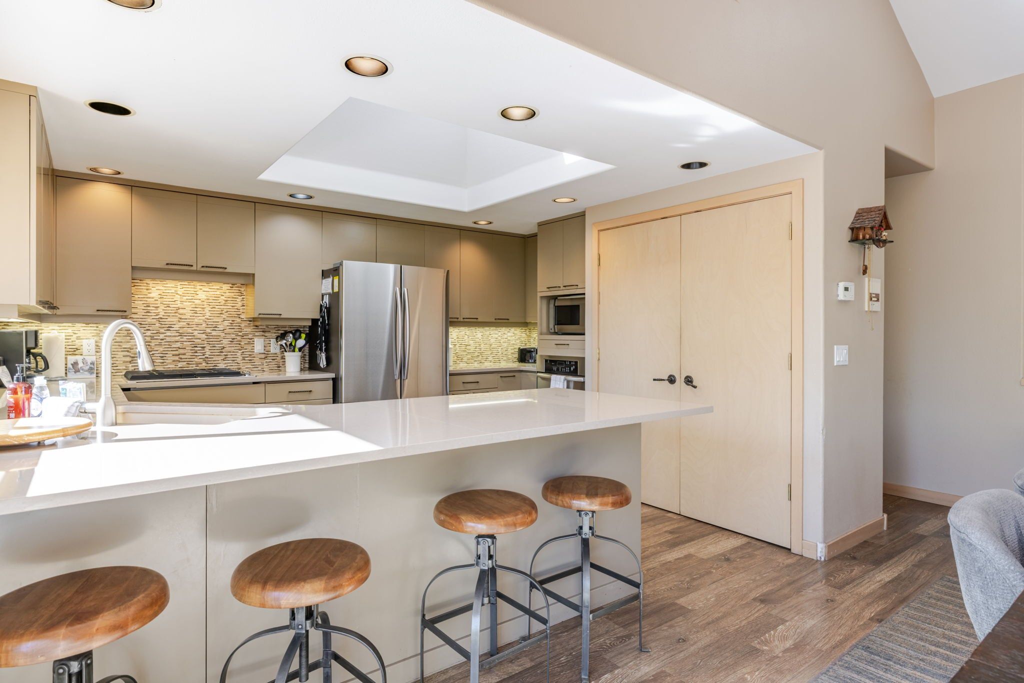 A modern kitchen with a central island, stainless steel appliances, and a stone backsplash.