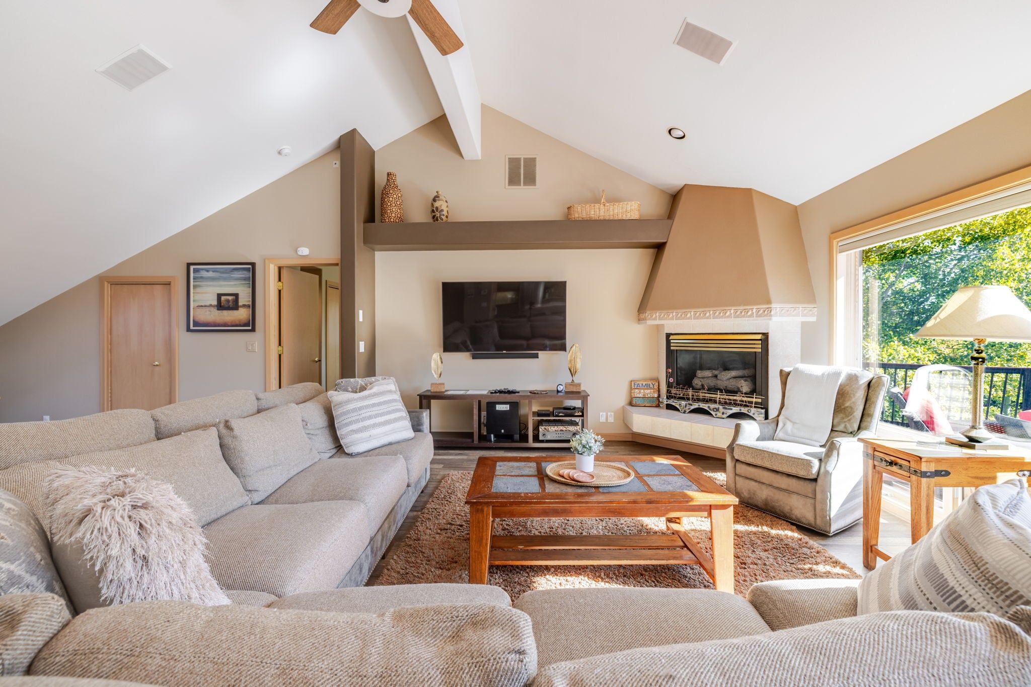 A spacious living room with a high ceiling, a fireplace, a television, and a comfortable seating area.