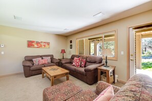 Ein Wohnzimmer mit zwei Sofas, einem Couchtisch und einem gestreiften Ottoman.