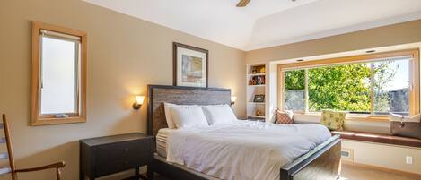 A bedroom with a bed, nightstand, chair, window, and ceiling fan.