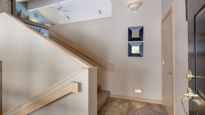 A staircase with wooden handrails and a light-colored wall. There are two wall-mounted light fixtures and a door with a brass handle. - Lone Eagle Landing 2 - Updated, A/C, Hot Tub, SHARC Passes (Sunriver)