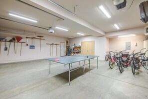 Ein großzügiger Innenbereich mit einer Tischtennisplatte, Fahrrädern und verschiedenen Werkzeugen an der Wand.