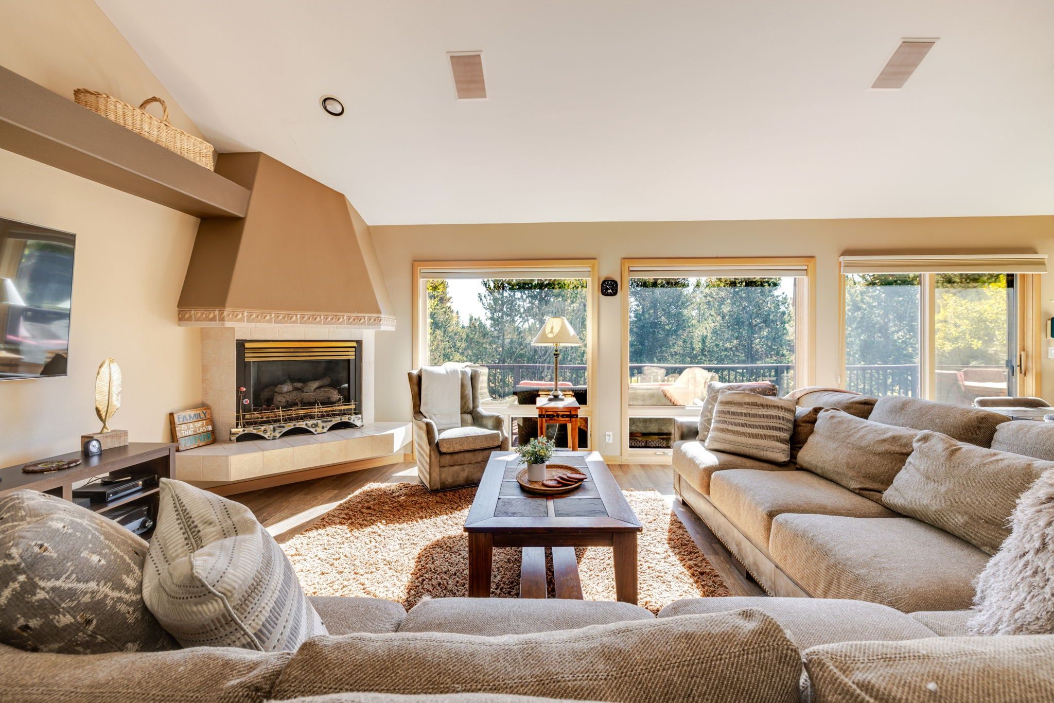 A living room with a fireplace, comfortable seating, and a view through large windows.