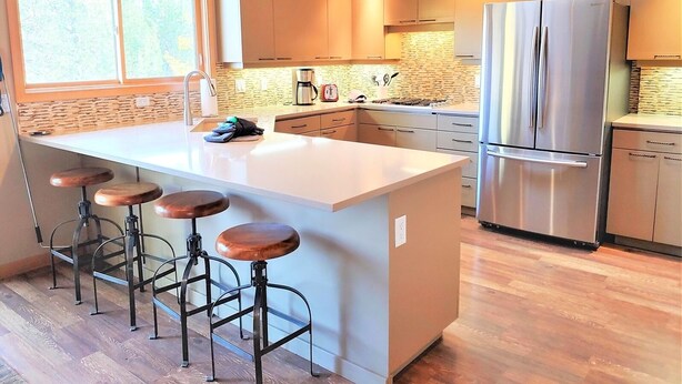 A modern kitchen with a large island, stainless steel appliances, and wooden bar stools. - Lone Eagle Landing 2 - Updated, A/C, Hot Tub, SHARC Passes (Sunriver)