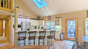 A spacious kitchen with a large island, white cabinetry, and a skylight.