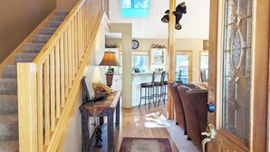 A staircase with wooden railings leading to a kitchen area with bar stools and a dining table.