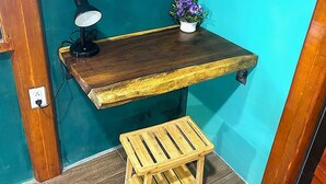 A teal wall with a wooden shelf holding a lamp and a potted plant. - Blue java banana (Tamarindo)