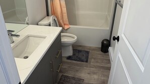 A bathroom with a sink, toilet, and shower. - 1 BHK private basement suite (Regina)