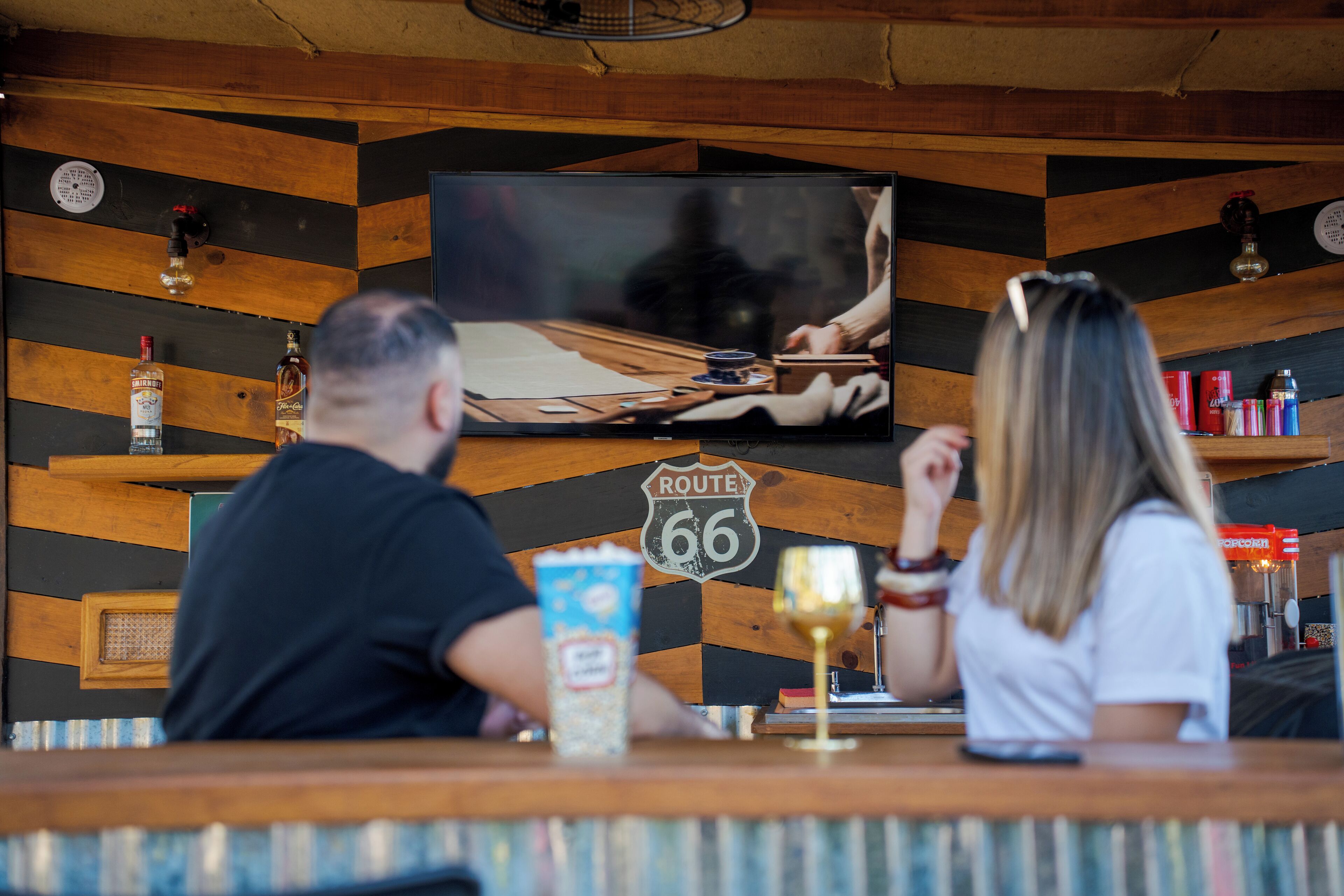 Baarialue, jossa on televisio, puukoristeet seinillä, Route 66 -kyltti ja erilaisia pulloja.