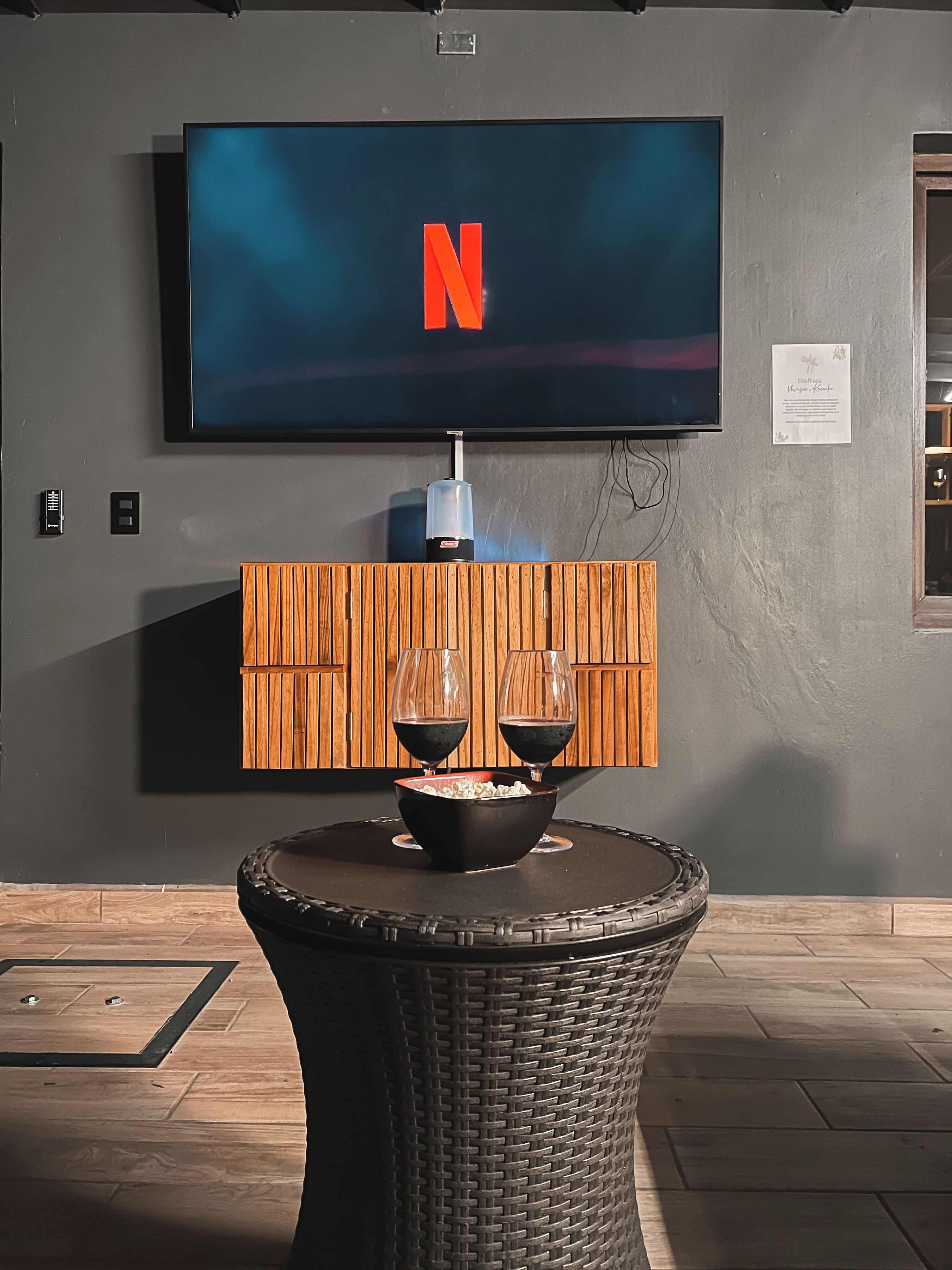 A modern room with a large flat-screen TV mounted on the wall displaying the Netflix logo.