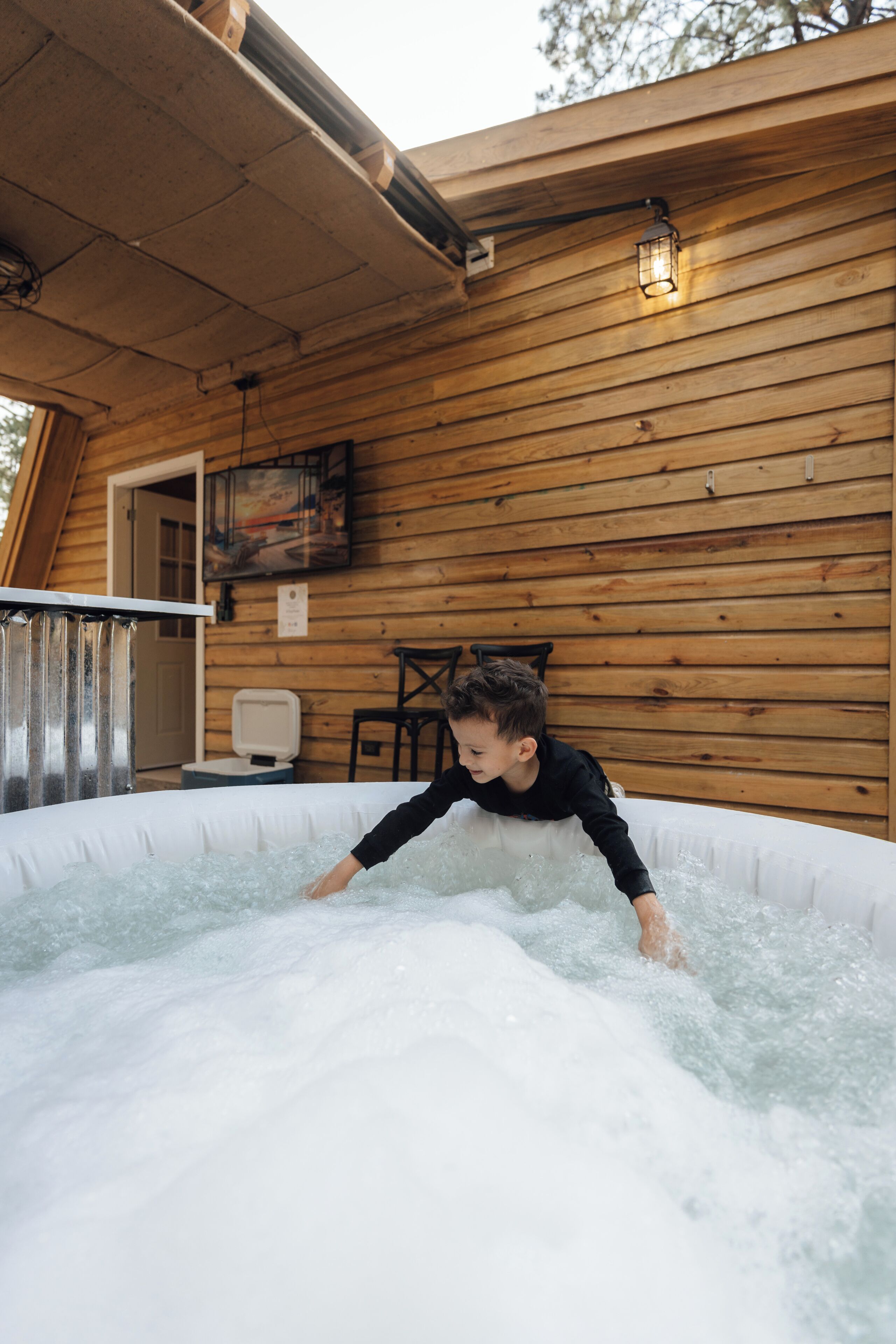 Une cabane en bois avec un jacuzzi, un tableau accroché au mur et une chaise.