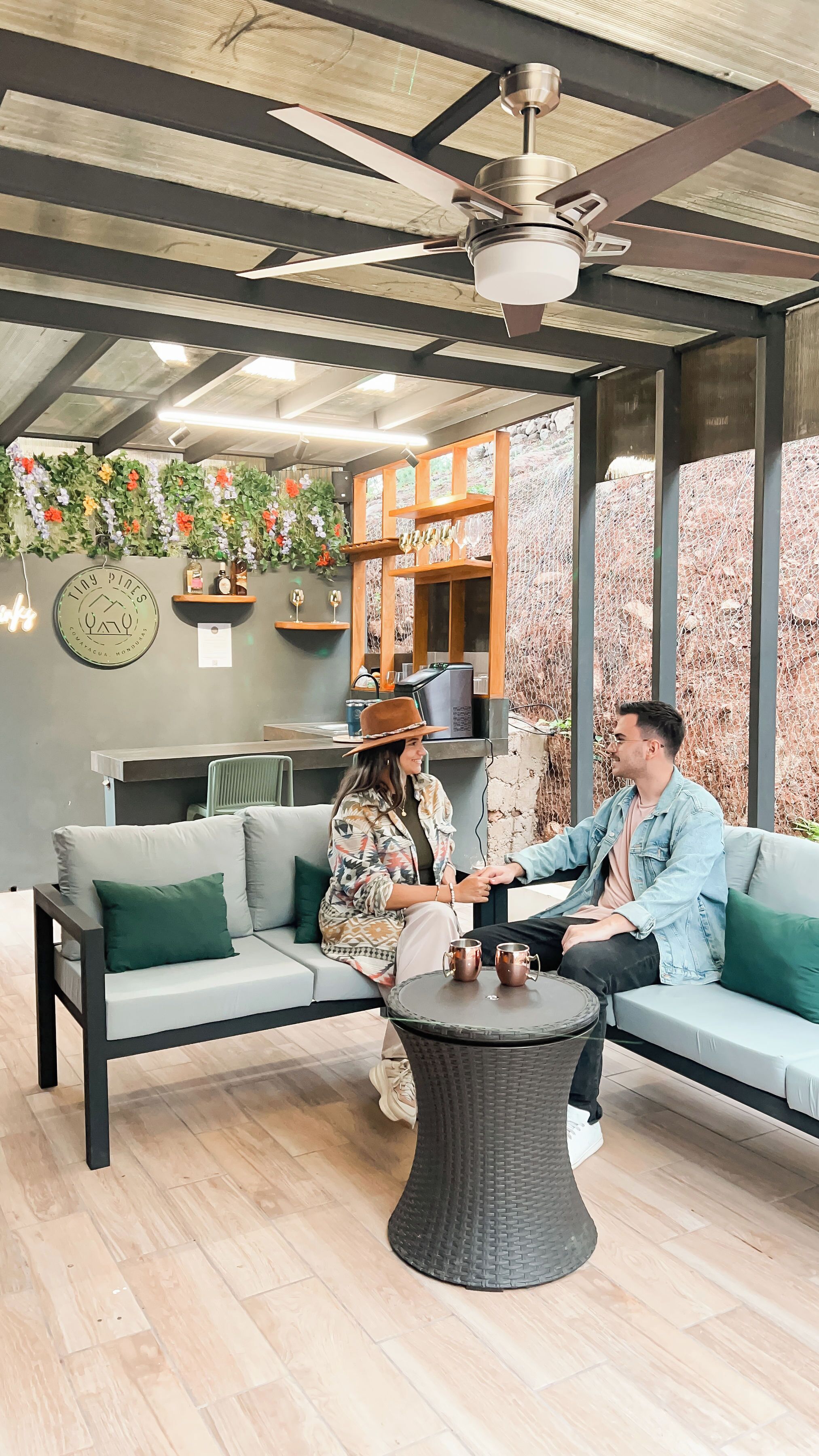A modern outdoor seating area with a ceiling fan, a round table, and a sofa with cushions.