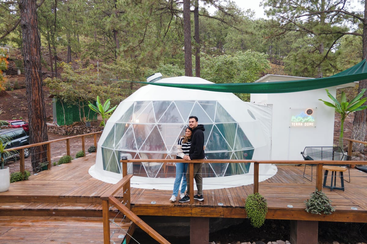 A geodesic dome structure with a wooden deck and a small outdoor seating area.