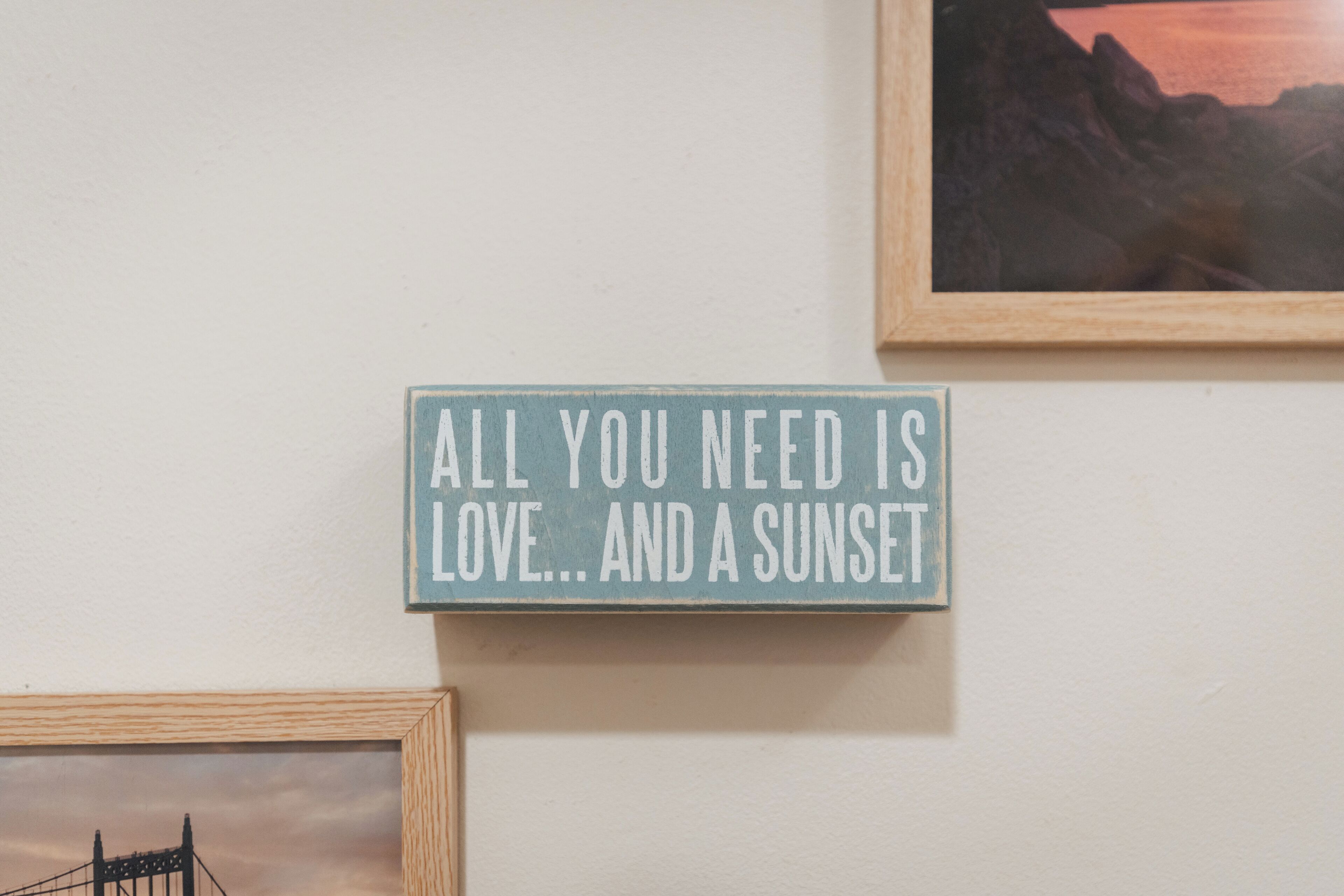 Een muur met een bord waarop staat: 'Alles wat je nodig hebt is liefde... en een zonsondergang.'
