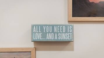 Een muur met een bord waarop staat: 'Alles wat je nodig hebt is liefde... en een zonsondergang.'