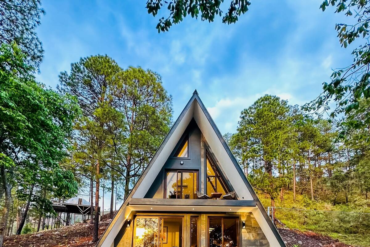 A modern house with a triangular roof, large windows, and a stone foundation.