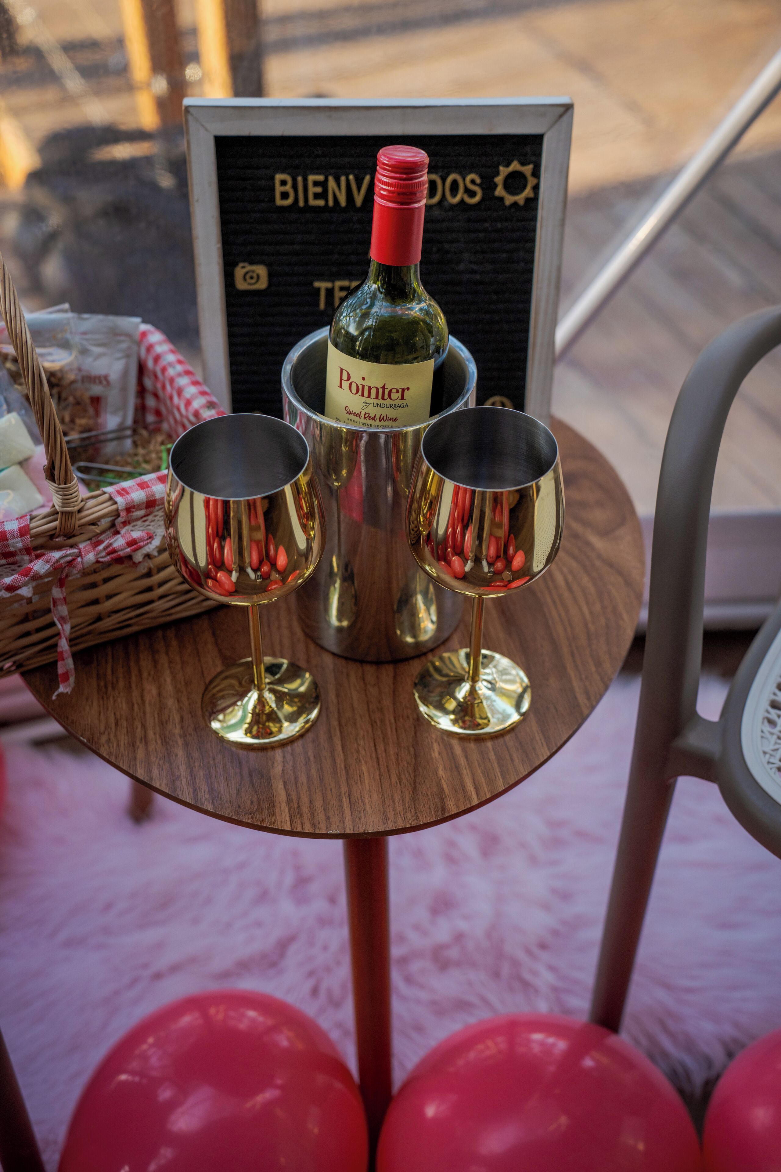 Una mesa con una botella de vino, dos copas de vino y un cartel que dice 'BIENVENIDOS'.