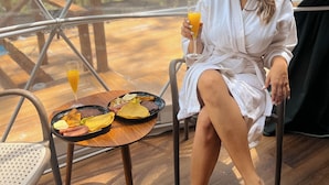 A person in a white robe sitting at a wooden table with a meal and a glass of orange juice.
