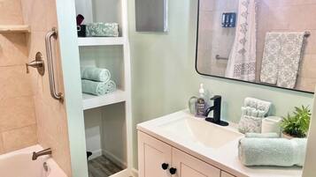 A bathroom with a bathtub, a sink with toiletries, and a mirror.