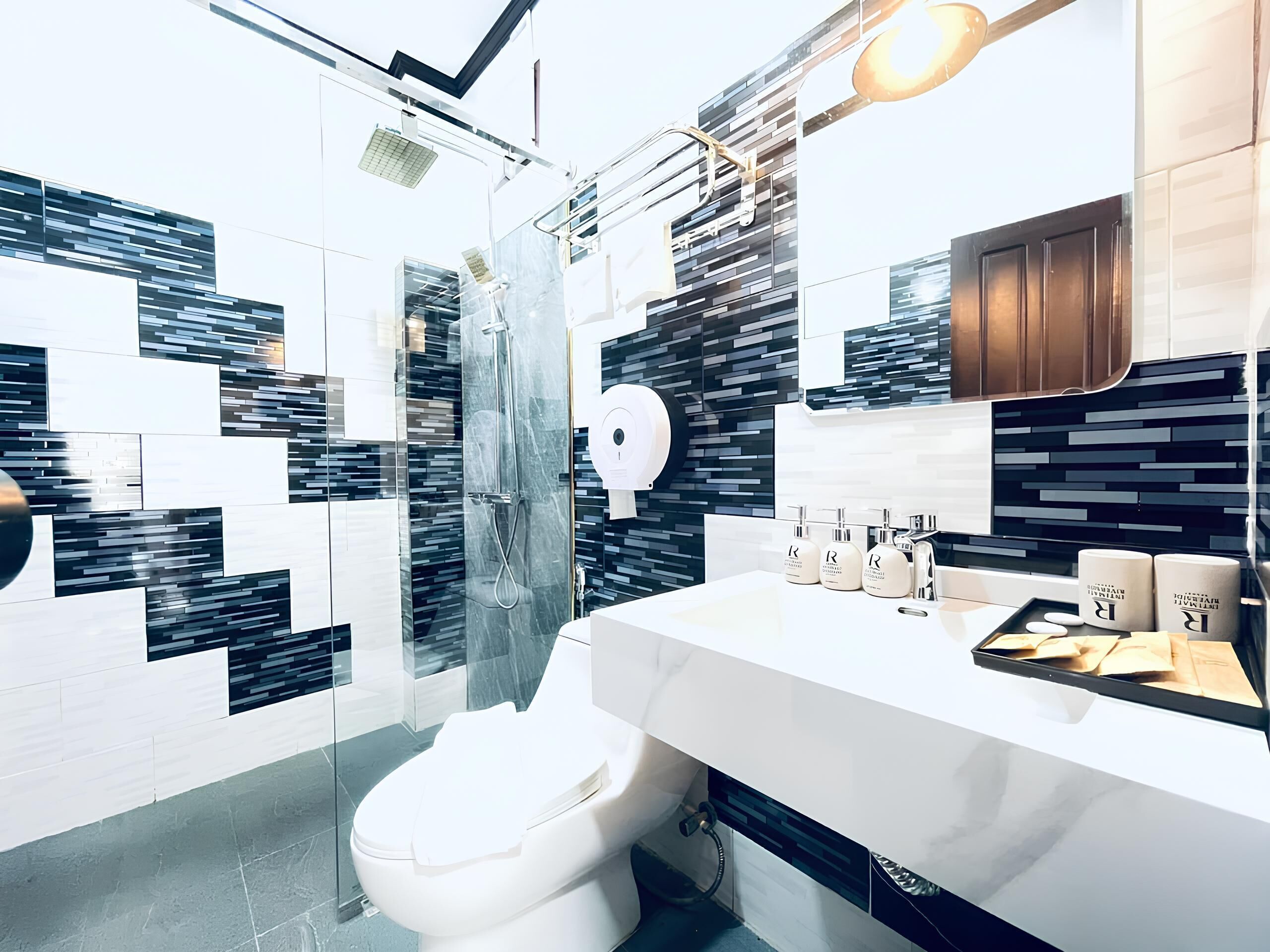 A modern bathroom with a glass shower enclosure, a white toilet, and a vanity with a mirror and toiletries.