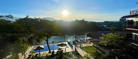 A resort with a pool, outdoor seating, and a view of the water and mountains.
